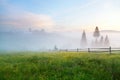 Foggy morning on the mountain meadow with wooden fence and spruce trees. Ukraine, Carpathians. Royalty Free Stock Photo