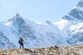 Beautiful landscape with mountains, blue huge glacier and silhouette of a man walking with a large backpack and guitar on the