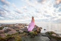 Beautiful landscape with nice cheerful woman in silk dress against sunset sky and clouds