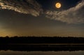 Beautiful landscape of night sky with cloud and bright full moon above silhouettes of trees at seaboard. Serenity nature Royalty Free Stock Photo