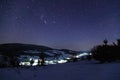 Beautiful landscape of the night starry sky in the Carpathians, Ukraine. Below you can see the night lights of the village