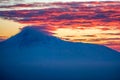 The top of the mountain is covered with clouds. Red clouds at the peak of the mountain during sunset. Beautiful sunset Royalty Free Stock Photo