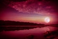 Beautiful landscape of red sky with cloud and full moon above silhouettes of trees at riverside. Serenity nature background, Royalty Free Stock Photo