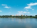 Beautiful landscape of the river, blue sky with white clouds and protruding buildings among green trees. Royalty Free Stock Photo