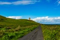 Beautiful landscape of a road between the Irish countryside with the Doonagore Castle tower in the background