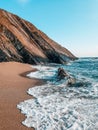 Beautiful landscape of rocky cliffs on the seashore, blue waves crashing on sandy beach Royalty Free Stock Photo