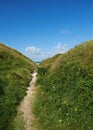 Beautiful landscape with a secret path between grassy hills to a hideaway, hidden beach or secluded area with a blue sky