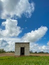 Beautiful landscape with a small abandoned white brick house in the middle of a green grass field under a blue sky with cumulus Royalty Free Stock Photo