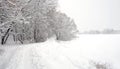 Landscape with snow-covered path on the edge of the forest and frozen river on a cloudy winter day Royalty Free Stock Photo