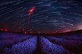 Beautiful landscape of a starry night with star trails over a field of lavender and red lights of wind turbines Royalty Free Stock Photo