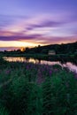 Beautiful landscape at sunset with purple sky and flowers and little house Royalty Free Stock Photo
