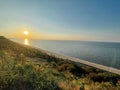 Beautiful landscape with sunset and sea. Sandy beach line with boats on the shore. Grass and bushes in the foreground. Wide angle Royalty Free Stock Photo