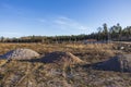 Beautiful landscape view. Beginning construction place with three piles of gravel of different sizes on forest trees and blue sky