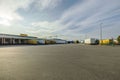 Beautiful landscape view of DHL logistic terminal. Huge territory with store boxes, trucks and cranes on pale blue sky.