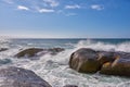 Beautiful landscape view of the rough ocean waves breaking on large boulders with a blue sky background. Tidal waves Royalty Free Stock Photo