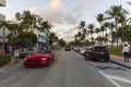 Beautiful landscape view of street of Miami Beach. White buildings, cars and palm trees on both sides of asphalt road.