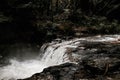 Beautiful landscape of a waterfall in a forest surrounded by fog and trees on a rainy day Royalty Free Stock Photo