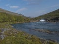 Beautiful landscape with waterfall on wild Tjaktjajakka river, birch tree forest and mountains. Lapland naturein summer at