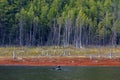 A fisherman on a rubber boat with oars floats on a calm lake amid green hills Royalty Free Stock Photo