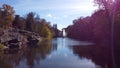 Lake, fountain, trees, large stones and lot of people walking sunny autumn day