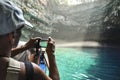 Tourist is taking photo of underground crystal cave lake.