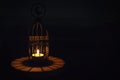 Beautiful Lantern that have moon symbol on top that have light from candle shining on wooden tray with dark background