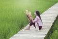 Beautiful Lao woman sitting alone with decorate flower on wooden bridge in green rice field