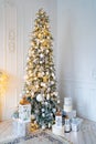 beautiful large elegant Christmas tree with gifts and lanterns in the white room