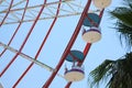 Beautiful large Ferris wheel and palm tree against blue sky, low angle view Royalty Free Stock Photo