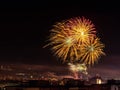 Beautiful large firework splashes high in the night sky over a city. Townspeople launching fireworks at New Year midnight.