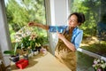 Beautiful Latin American pregnant woman, florist entrepreneur photographing a bouquet of orchid flowers in wicker basket