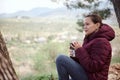 Beautiful Latin American young woman tourist, traveler adventurer relaxing in the forest, with a thermos mug in hands Royalty Free Stock Photo