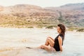 latin caucasian woman wearing one piece swimming suit, smiling on sandy beach enjoying waves