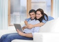 Beautiful latin couple in love lying together on living room sofa couch enjoying using digital tablet Royalty Free Stock Photo