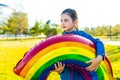 beautiful latin hispanic seven years old girl with big rainbow balloon outdoors in summer park
