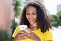 Beautiful latin woman with curly hair sending message with phone Royalty Free Stock Photo