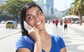 Beautiful latin woman with long dark hair at phone in city Royalty Free Stock Photo