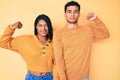 Beautiful latin young couple wearing casual clothes together strong person showing arm muscle, confident and proud of power