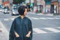 Beautiful Latin young woman in grey stylish poncho with fringe in urban street. Fashion and street style. Pretty hispanic brunette