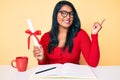 Beautiful latin young woman with long hair holding graduate degree diploma smiling happy pointing with hand and finger to the side Royalty Free Stock Photo