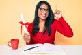 Beautiful latin young woman with long hair holding graduate degree diploma smiling with an idea or question pointing finger with Royalty Free Stock Photo