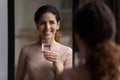 Beautiful latina lady stand by mirror hold glass of water