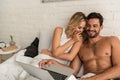 Laughing couple using laptop in bed in the morning Royalty Free Stock Photo