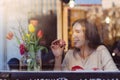 Beautiful laughing young woman sitting in coffee shop near the window,drining coffee and eating dessert