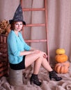 Beautiful legged redhead  girl in shiny stockings and black miniskirt posing on Halloween party. Royalty Free Stock Photo