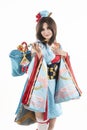 Beautiful leggy busty cosplayer girl wearing a stylized Japanese kimono costume cheerfully posing holding a fake pipe in the wind