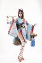 Beautiful leggy busty cosplayer girl wearing a stylized Japanese kimono costume cheerfully posing holding a fake pipe in the wind