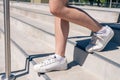 Beautiful Legs of a Caucasian or Hispanic woman in white sneakers walking down a concrete stairs. Horizontal orientation Royalty Free Stock Photo