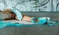 Beautiful legs and feet of a sexy young artistically abstract painted woman lying on the studio floor, ballerina with orange, blue