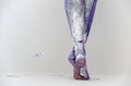 Beautiful legs and feet of a young artistically abstract painted woman with white, gray and purple paint. Creative body art